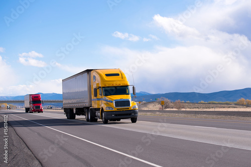 Caravan modern semi trucks on straight highway on plateau