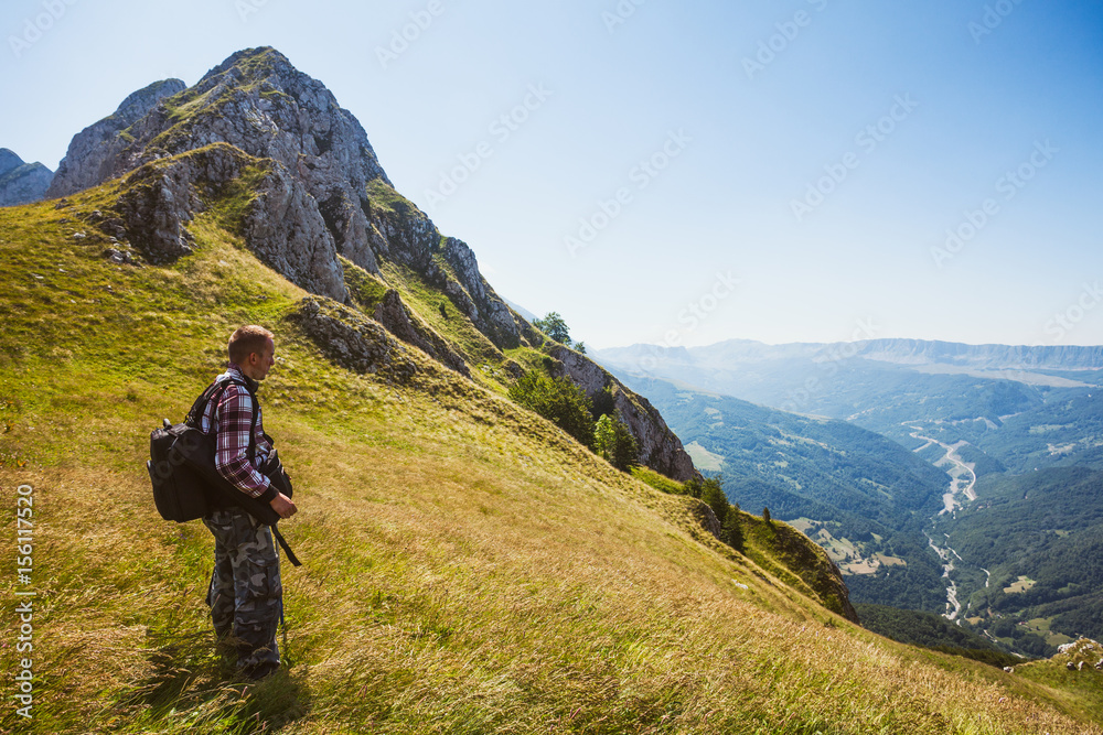 Hiker standing at viewpoint in mountain and looking at valley.