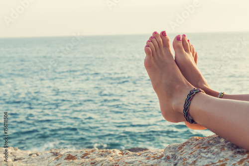 Girl's feet with ocean / sea tropical background.
