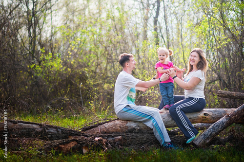  Family is resting in nature. Father throws her daughter up. Mom catches up with her daughter. Happy family on vacation at a picnic. Family photo in spring, summer © Nelly