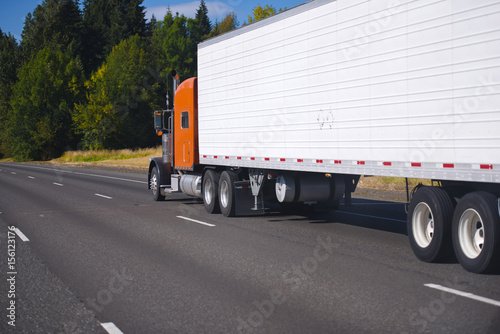 Orange classic semi truck and trailer on highway