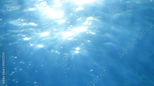 Beautiful underwater sea scene view with natural light rays, shining through the water's glittering, moving surface and blurred bokeh