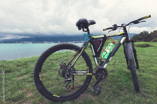 A bicycle stands on a green lawn of the sea coast with a view of the mountain range concept of active recreation and healthy lifestyle