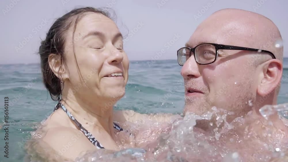 Family middle-aged couple fooling around happily in the sea. Close-up bald man and his woman. Spend their holidays at the resort. Family middle-aged couple fooling around happily in the sea. Close-up bald man and his woman. Spend their holidays at the resort.