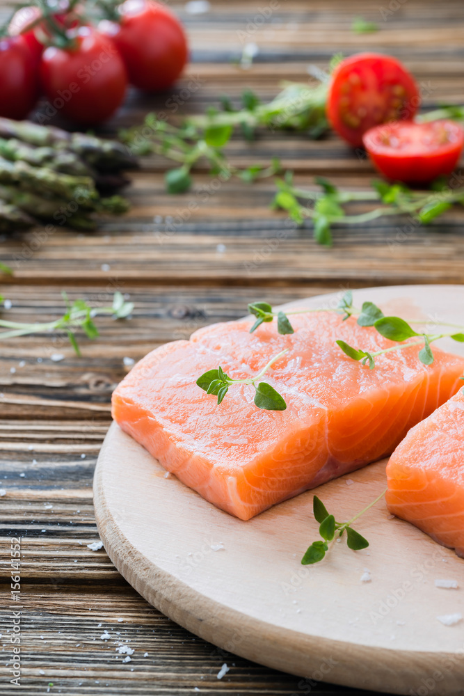 Raw uncooked salmon and vegetables on wooden table Raw uncooked salmon and vegetables on wooden table