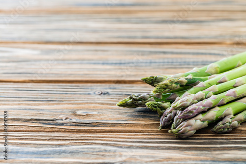 Raw green asparagus bunch on wooden table. Copy space