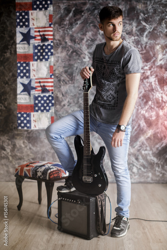 Young handsome musician with electric guitar on dark background