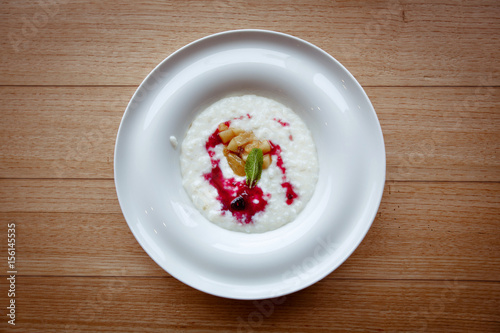 Rice porridge in plate with berries wooden table.