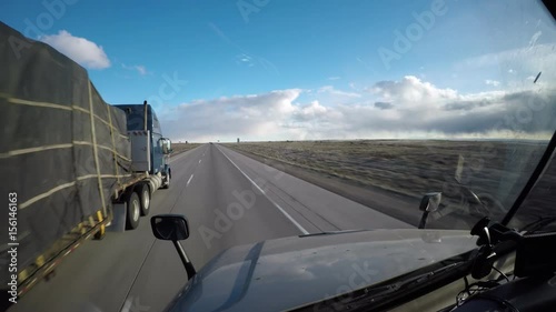 A Flatbed Semi Truck Passes the viewer on a rural highway in Idaho, USA.
