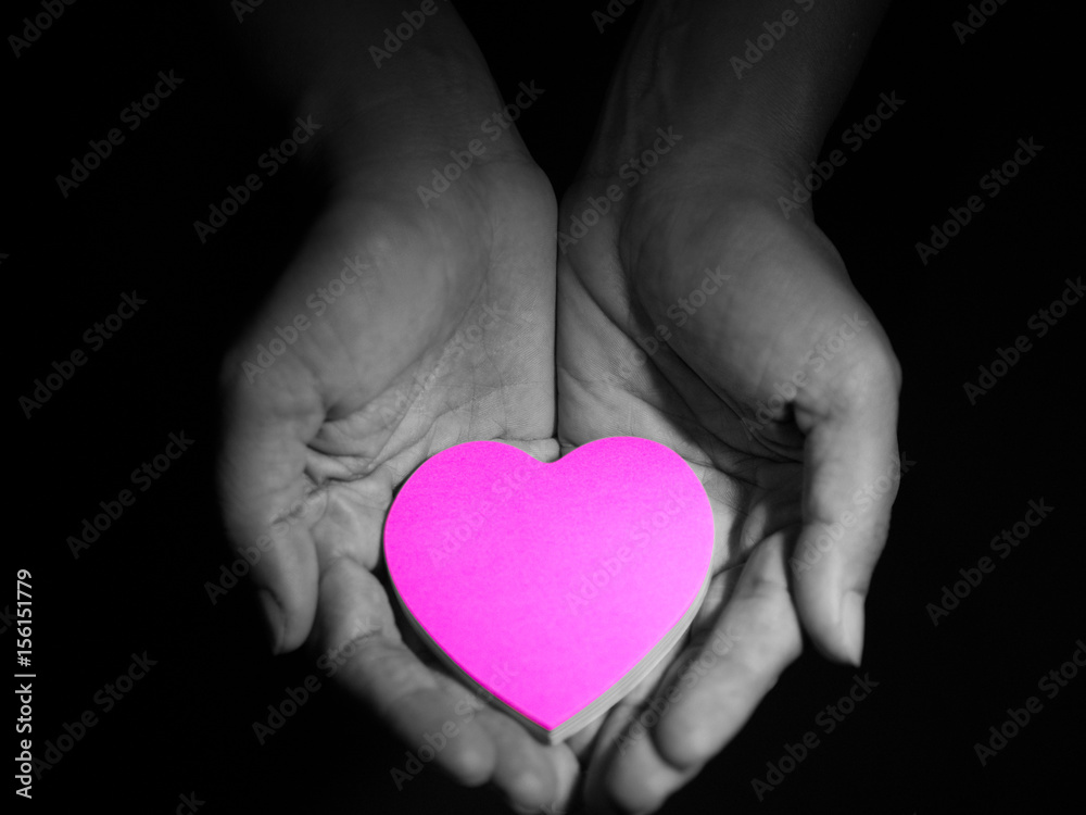Pink heart in woman hands, low key picture style, dark and black background. love concept. Pink heart in woman hands, low key picture style, dark and black background. love concept.
