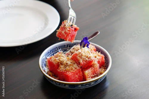 Watermelon with Sweet Dried Fish-Crispy Shallot Dip - Fresh Watermelon chunks thoroughly speckled with a sugary dip of dried fish flakes and crispy shallots, Royal Thai cuisine, Selective Focus.