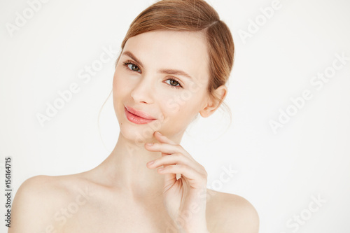 Portrait of naked beautiful girl with natural make up smiling looking at camera over white background. Health and beauty lifestyle.
