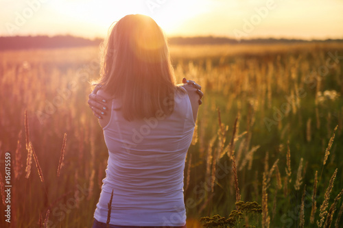 Young girl hugging herself on a sunny field. Instagram