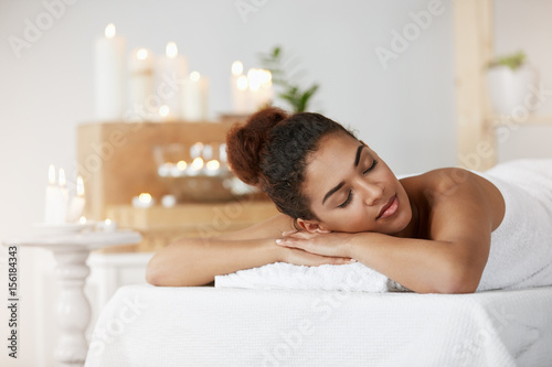 Tender african girl resting relaxing with closed eyes in spa salon.