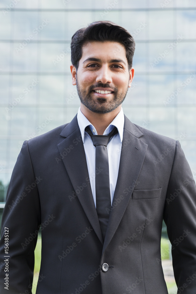 Smiling businessman or worker standing in suit near office building Smiling businessman or worker standing in suit near office building