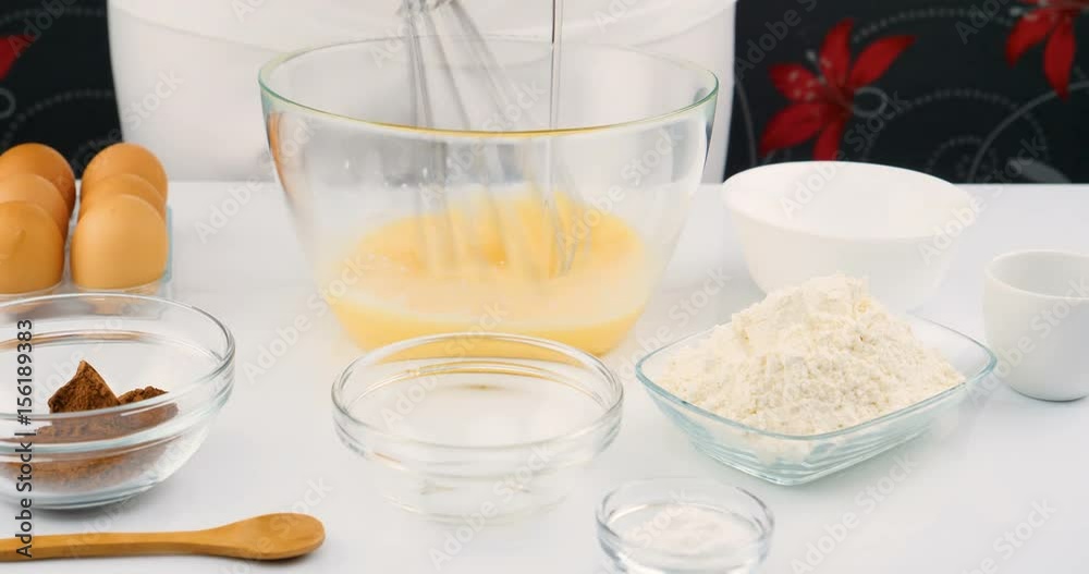 Female hand pouring oil and cocoa into a bowl of mixed eggs to cook a cake.  Whisking ingredients for homemade cake. Chef mixing dough in mixing bowl.