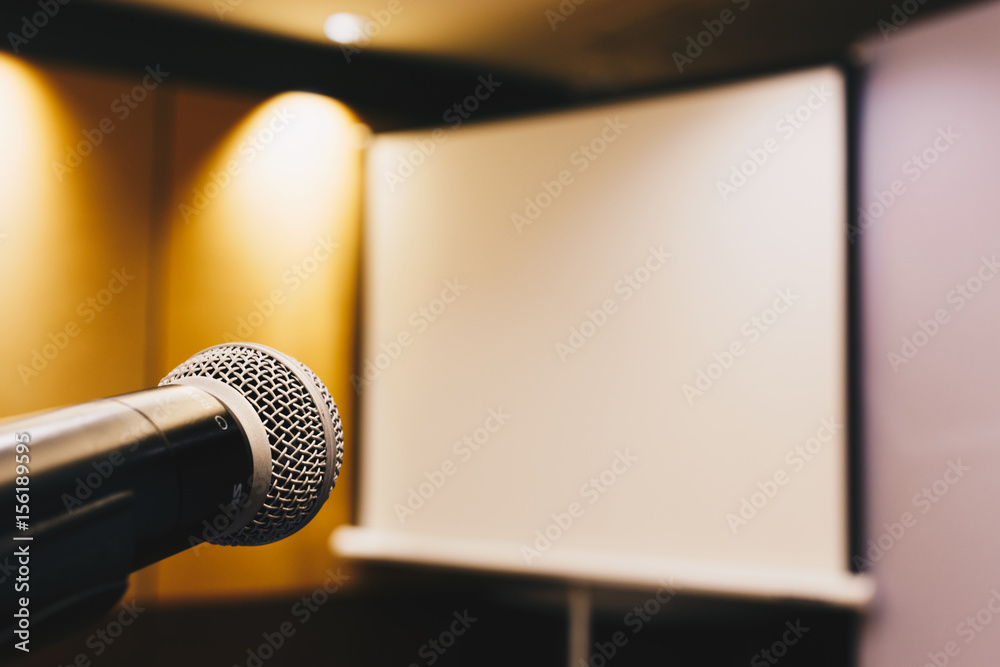 Obraz premium microphone ready to use in the podium and the projector screen on the back of the meeting room for the press conference. selective focus. vintage photo and film style.