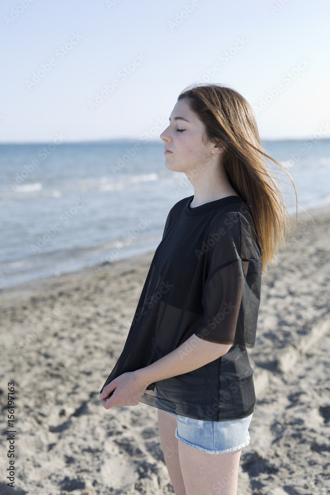 Teenage girl with closed eyes isolated on the beach. Teenage girl with closed eyes isolated on the beach.