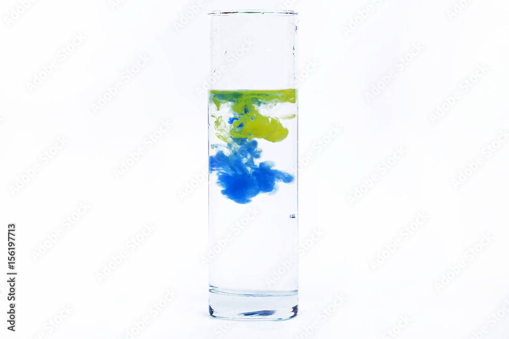 Blue and yellow paint fall in a glass with water Blue and yellow paint fall in a glass with water
