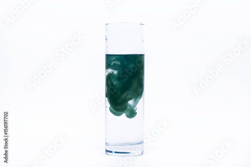 Blue paint falls in a glass with water