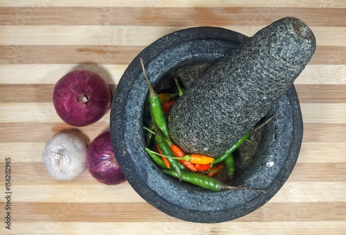 Mortar and pestle with fresh chilis, onion and garlic