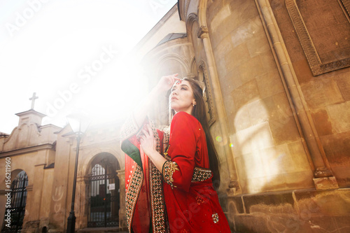 Woman dressed like an Indian bride in red sari stands on the square
