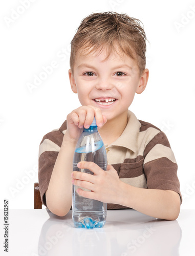 Portrait of cheerful little boy with plastic bottle of water. Cute smiling child drinks water, isolated on white background.