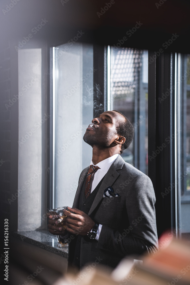 confident businessman holding cigar and glass of alcohol in hands confident businessman holding cigar and glass of alcohol in hands