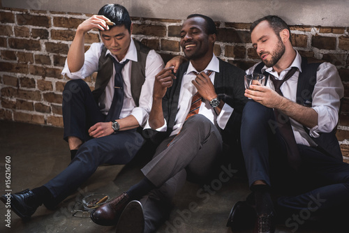 group of tired stylish businessmen resting together after work