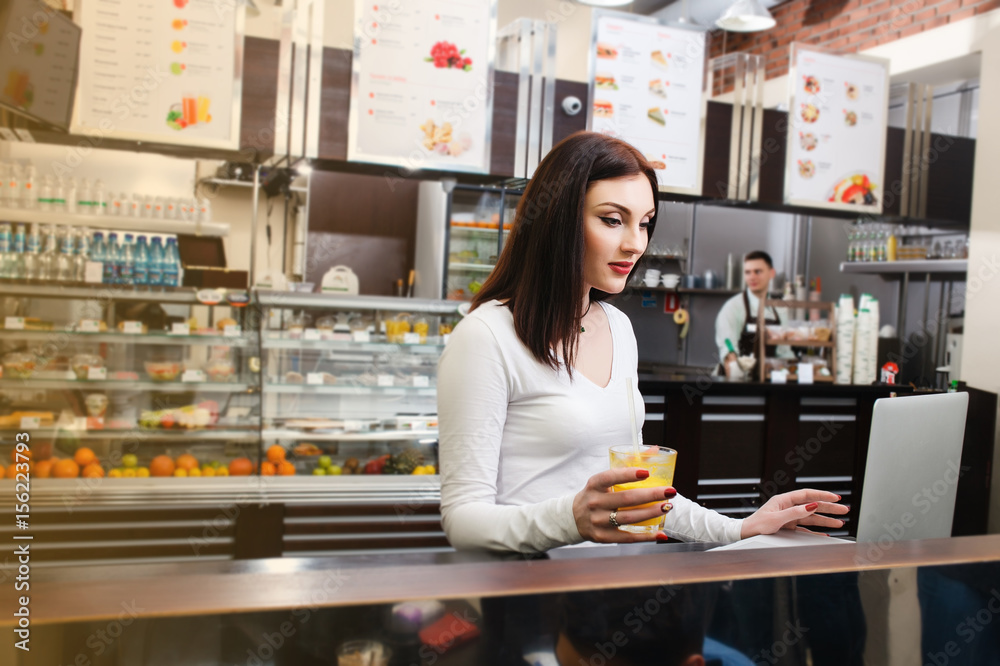 Young woman in a white blouse sits at a table and use her laptop in a cafe Young woman in a white blouse sits at a table and use her laptop in a cafe