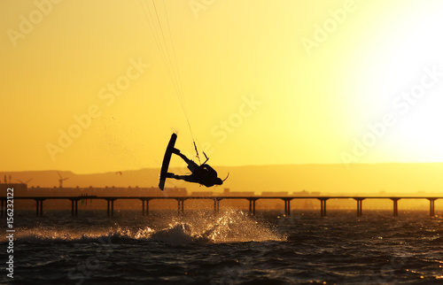 Kiteboarder sportsman under sunset sun  freestyle kiteboarding rider on the evening kitesession  sunset in the sea  extreme watersports  active lifestyle  recreation hobby and fun time