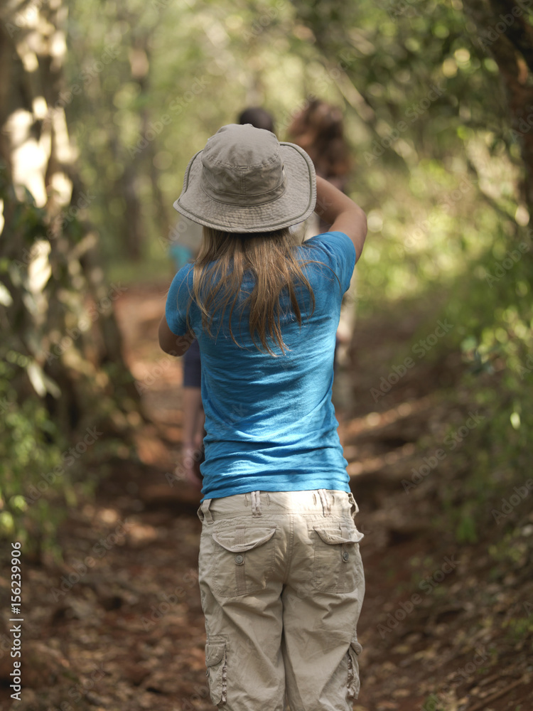 Rear view of a teenager girl walking down a path surrounded by trees, Africa