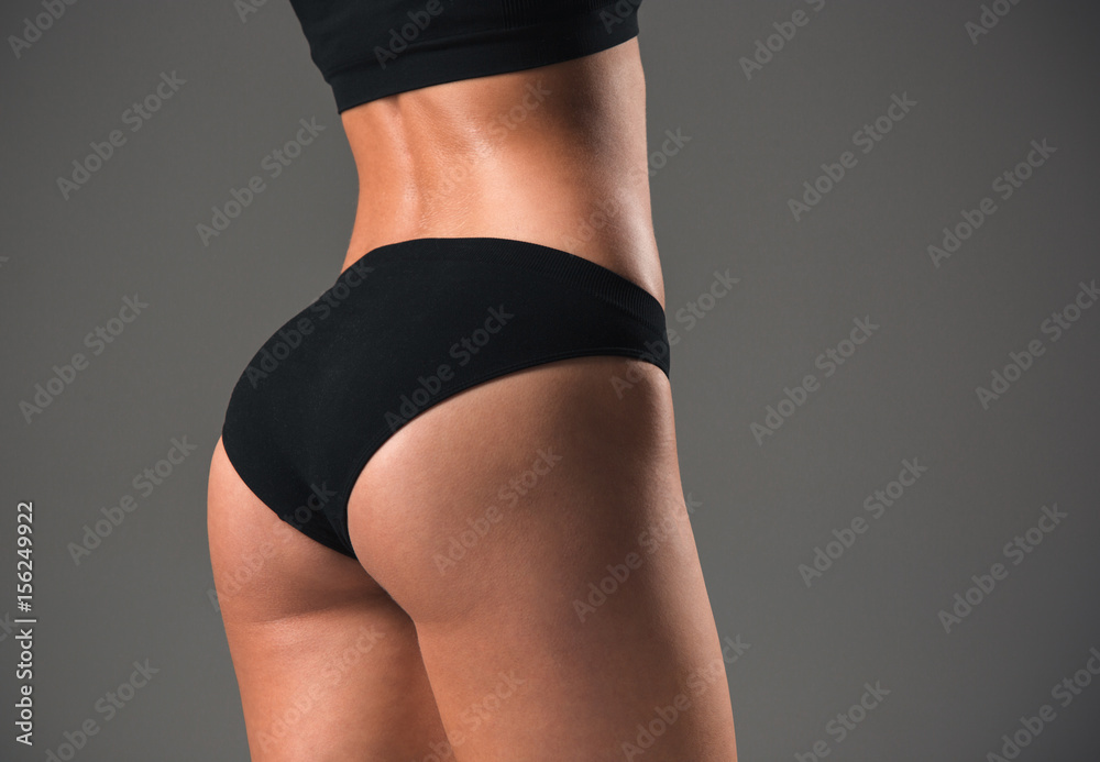Fototapeta premium Muscular young woman athlete on gray