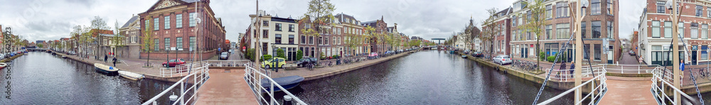 AMSTERDAM - APRIL 2015: Tourists walk along city canals. The city attracts 15 million people annually
