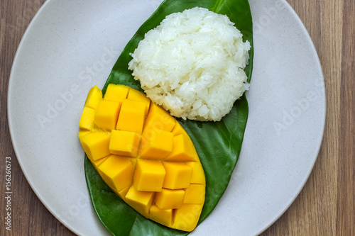 Closeup macro shot dish of carve beautiful yellow mango with sticky rice on wooden table