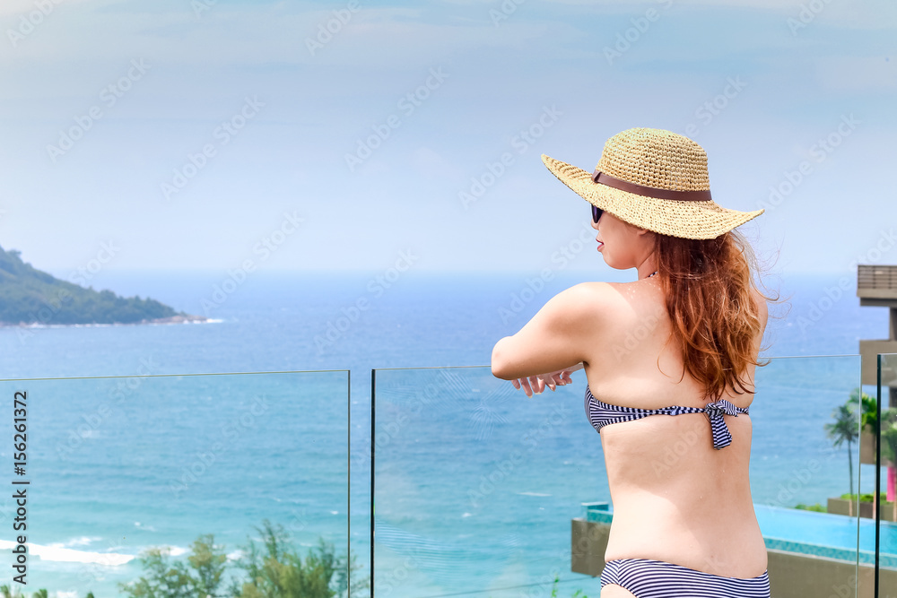 Woman in bikini is standing on the edge of swimming pool