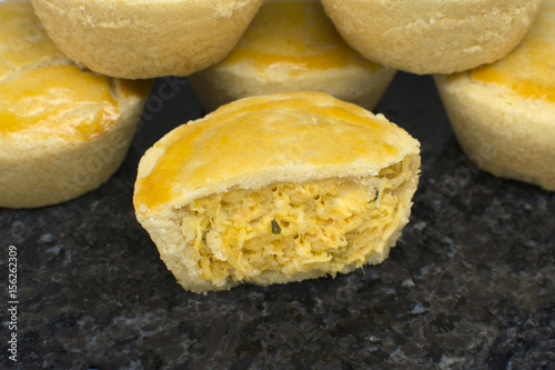 Traditional mini chicken pie called empadas with one open in granite platter photo