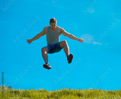 Jumping up guy. Background blue sky. Below the green grass