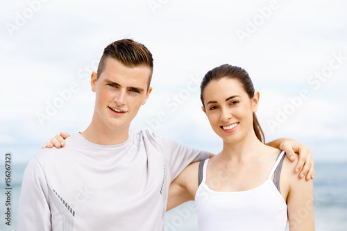 Young couple looking at camera while standing next to each other on beach © Sergey Nivens