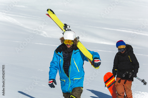 Skier skiing on fresh white snow with ski slope on Sunny winter day