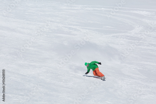 Male snowboarder snowboarding on fresh snow on ski slope on Sunny winter day in the ski resort in Georgia. Travel adventure concept. space for text