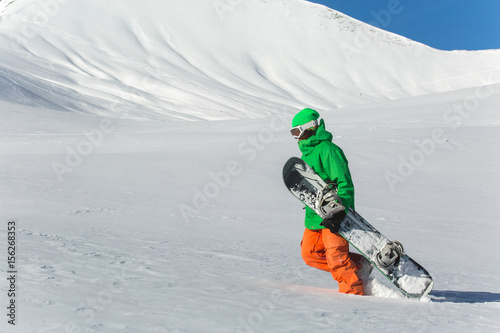 Male snowboarder snowboarding on fresh snow on ski slope on Sunny winter day in the ski resort in Georgia. Travel adventure concept. space for text