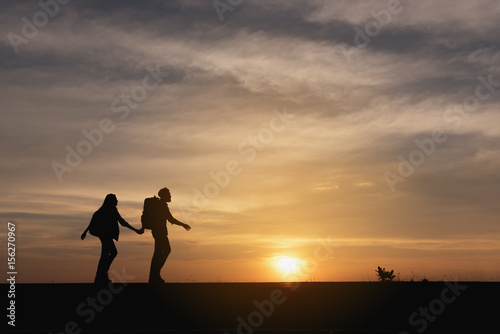 Silhouette of the Couple walking on the road near the sea. Family travel and healthy lifestyle concept.