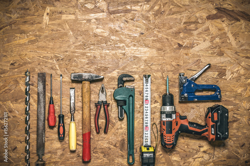 A set of hand tools in a row on the panel of OSB