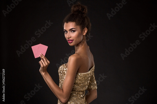 Woman winning - Young woman in a classy gold dress holding two cards, a poker of aces card combination.