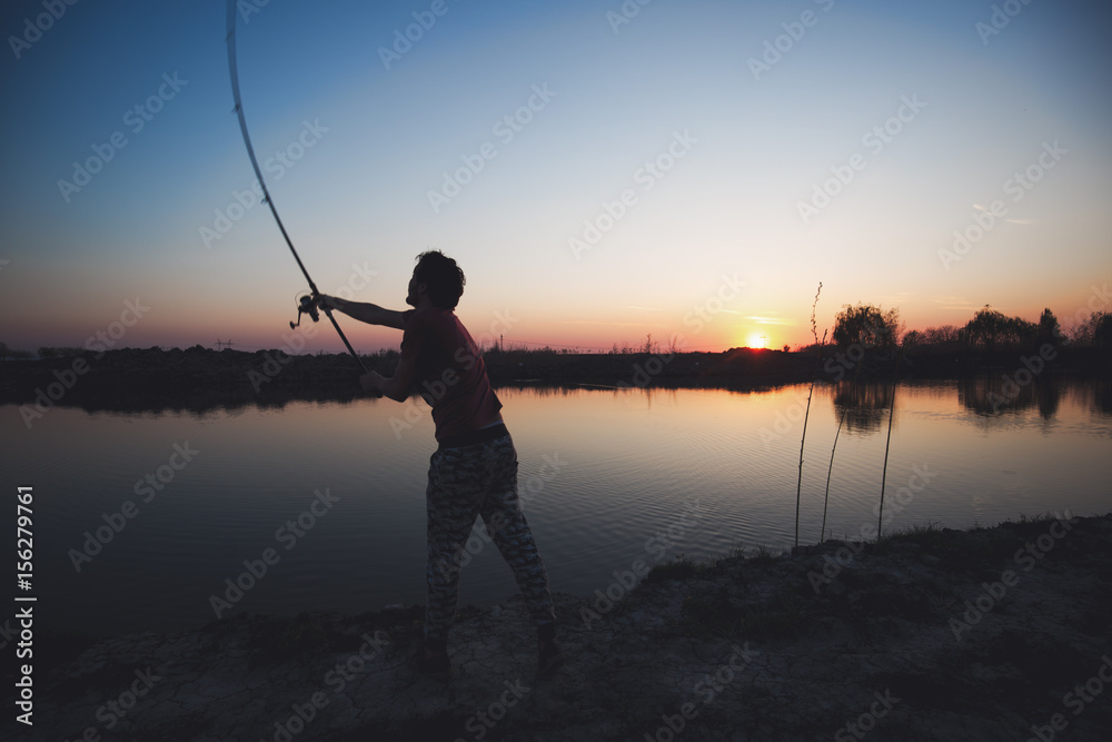 Fishing as recreation and sports displayed by fisherman at lake Fishing as recreation and sports displayed by fisherman at lake