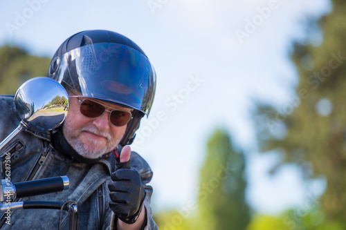 ein Motorradfahrer sitzt auf seiner Maschine und grüßt freundlich © Rainer Fuhrmann
