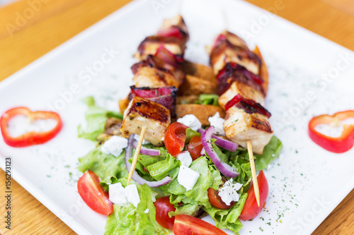 Grilled skewers with vegetables and meat in a herb marinade isolated on white plate.