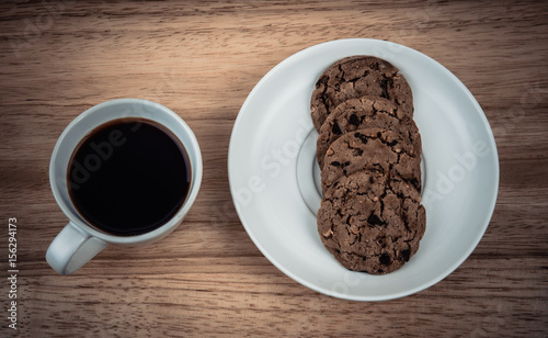 Mug of coffee with cookies on wooden table