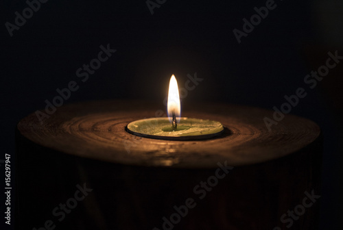 A candle shines in the dark. In a wooden candlestick